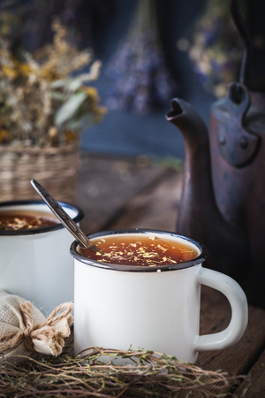 Rustic enameled mugs of healthy herbal tea, vintage tea kettle and healing herbs.の写真素材