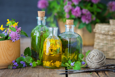 Bottles of tincture or infusion of healing herbs, mortar, scissors, medicinal herbs on wooden board. Herbal medicine concept.の写真素材