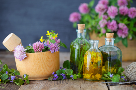 Bottles of tincture or infusion of healthy herbs, healing herbs and wooden mortar of flowers on rustic table. Herbal medicine.の写真素材