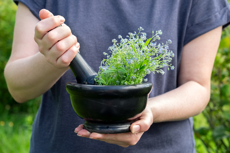 Woman holding a mortar of healing herbs and pestle. Herbal medicine.の写真素材
