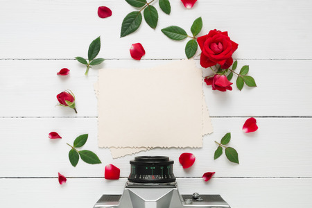 Retro empty photo frame for the inside, retro camera  and red rose flowers on white background. Flat lay, top view.の写真素材