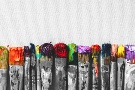 Row of artist paintbrushes with colorful bristle closeup on artistic canvas background, retro black and white stylized.の写真素材