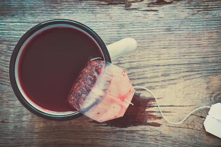 Tea bag of red fruit and berries tea in brewing tea in enameled mug.の写真素材