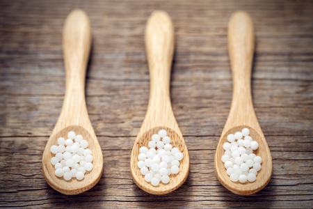 Three woodens spoon of homeopathic globules. Homeopathy medicine.の写真素材