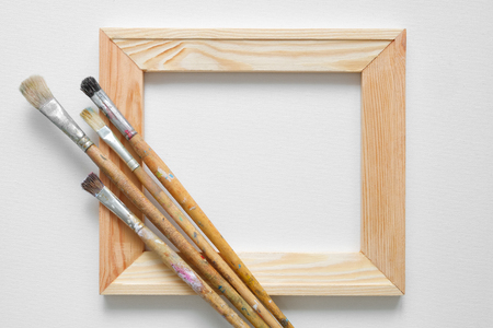 Wooden stretcher bar and paintbrushes on white artist canvas background. Top view. Copy space for text.の写真素材