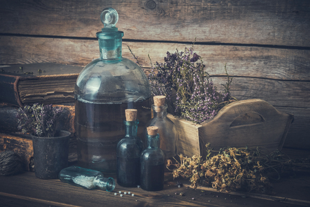 Tincture bottles, vial of homeopathy globules, old books, dry healthy herbs and curative drugs. Herbal and homeopathic medicine.の写真素材