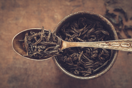 Vintage metal cup of dry green tea leaves and spoon. Top view. の写真素材