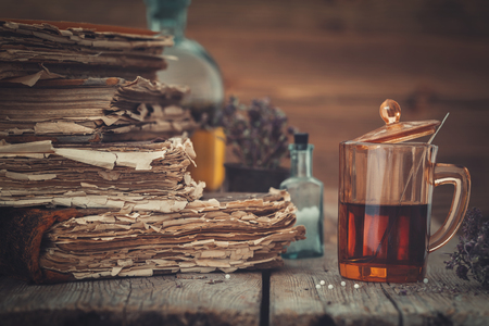 Old books, tincture or healthy tea in glass, vial of homeopathic globules and medicinal herbs. の写真素材