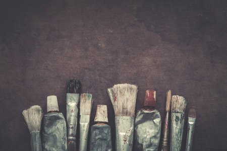 Artist paintbrushes, paint tubes closeup on dark canvas background. Retro stylized. Copy space for text.の写真素材