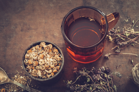 Cup of healthy tea, rustic mortar of daisy herbs, dried thyme on table. Herbal medicine.の写真素材