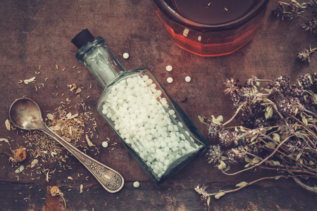 Bottle of homeopathic globules, bunch of dry healthy herbs and glass of tincture or healthy tea. Top view.の写真素材