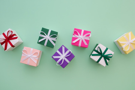 Gift boxes with ribbons on pastel green background. Top view, flat lay. Copy space for text.