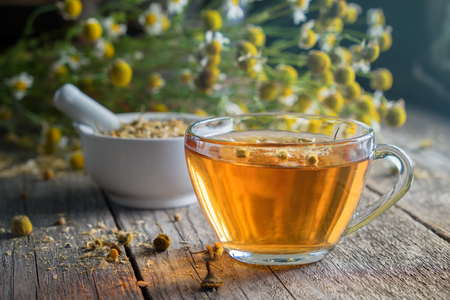 Healthy chamomile tea or infusion, mortar and daisy herbs on wooden table.の写真素材