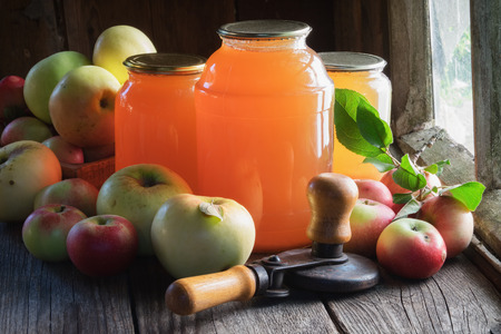 Glass jars of apple juice, apple fruits and can lid closing machine for canning.の写真素材