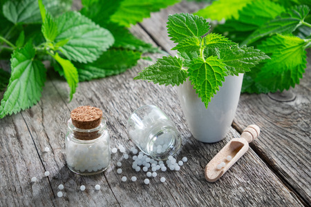 Nettle healing herbs, mortar and bottles of homeopathic globules. Homeopathy medicine.の写真素材