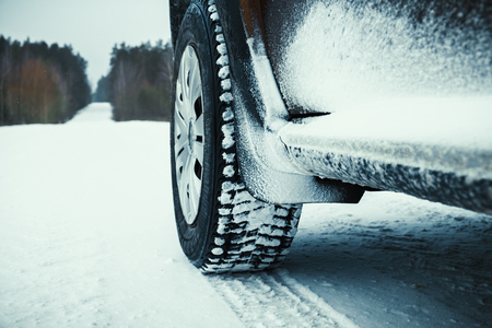 Car tires covered with snow on winter road through forest.の写真素材