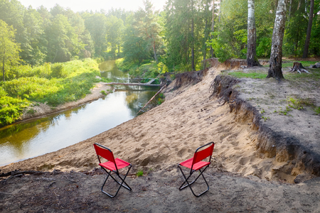 Beautiful landscape of forest river and two tourist chairs, Belarus.の写真素材