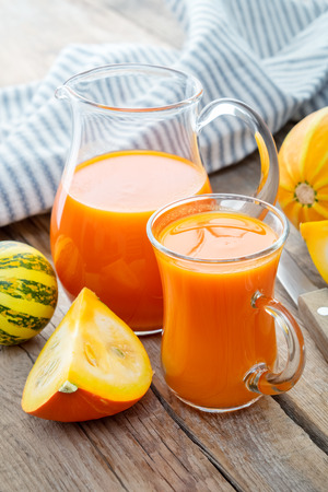 Glass jug and cup of pumpkin juice and pumpkins.の写真素材