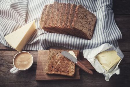 Toast bread slices, butter, cheese and coffee cup for breakfast on kitchen table. Top view.の写真素材