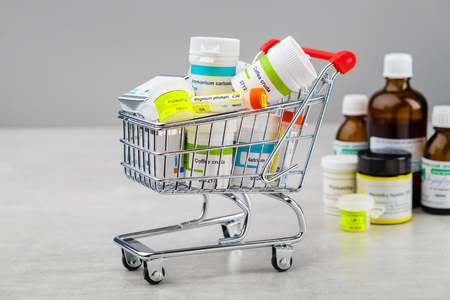 Mini shopping cart full of homeopathic remedies with typical international names.の写真素材