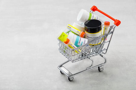 Mini shopping cart full of homeopathic remedies with typical international names.の写真素材