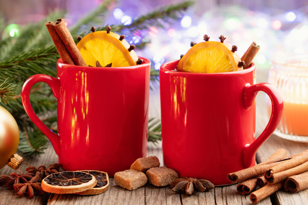 Red mugs of hot mulled wine with spices and citrus fruitsの写真素材