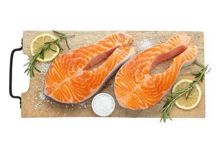 Two raw salmon fish steaks with lemon slices, salt and rosemary on cutting board. Top view, isolated on white.の写真素材