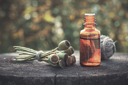 Poppy flower heads and bottle of infusion. Herbal or homeopathic medicine.の写真素材