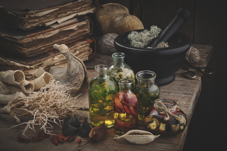 Bottles of essential oil, mortar of dried moss, old books, dry roots and plants. Herbal medicine.の写真素材