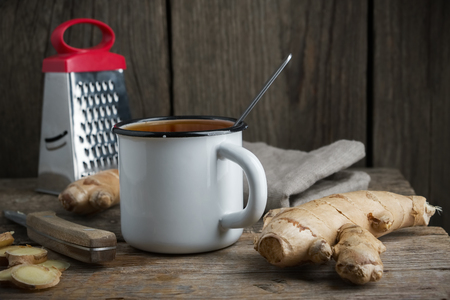 Healthy ginger tea cup, ginger root and grater on wooden table.の写真素材