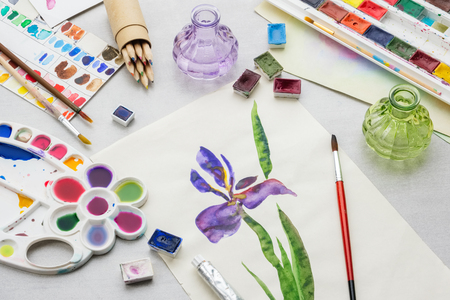 Watercolor drawing - Iris flower - and artistic equipment on desk. Top view.の写真素材
