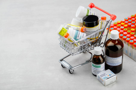 Minsk, Belarus - Oktober 26, 2019: Mini shopping cart full of homeopathic remedies and first aid kit with different homeopathic preparation. Concept of buying homeopathic drugs.のeditorial素材