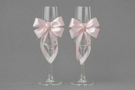 Two wedding wine glasses decorated with pink ribbons.の写真素材