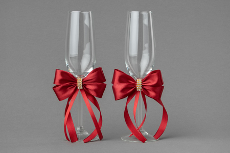 Two wedding wine glasses decorates with red silk bows.の写真素材