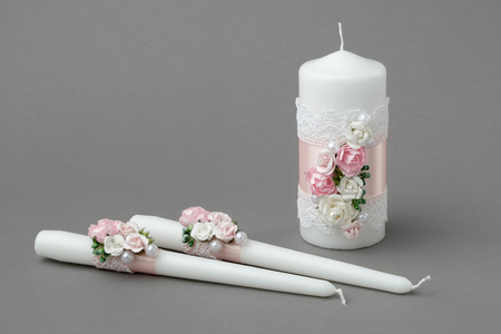 Three candles decorated with beautiful roses, pearls, pink silk ribbons and lace.の写真素材