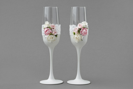 Two wedding wine glasses decorated with lace and roses on grayの写真素材