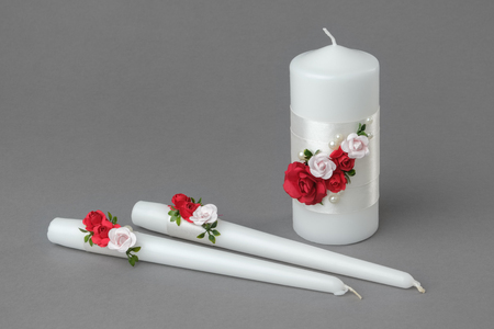 Three candles decorated with red and pink roses on grayの写真素材