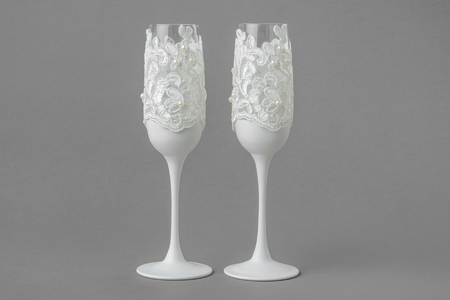 Two white wedding wine glasses decorated with lace and pearls.の写真素材