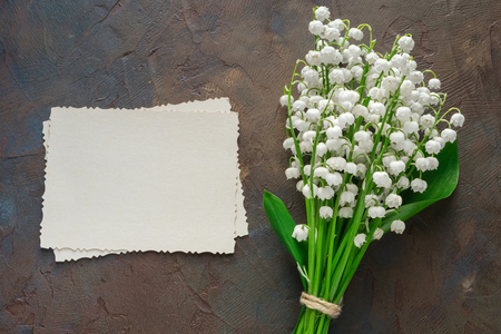 Retro empty photo frame for the inside and Lilies of the valley bouquet on dark brownの写真素材