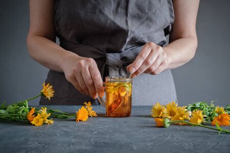 Woman making healthy tea with calendula or marigold flowers.の写真素材