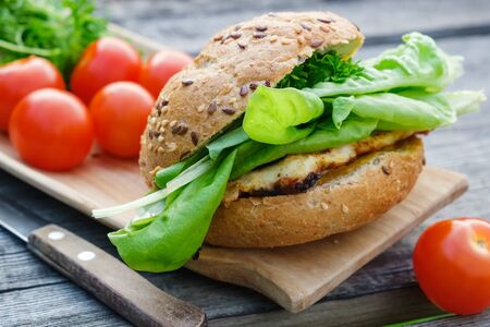 Tasty homemade burger with meat, lettuce, tomatoes, sesame bun on wooden picnic table outdoors.の写真素材