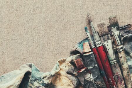 Artist paint brushes, paint tubes closeup on brown linen canvas.の写真素材