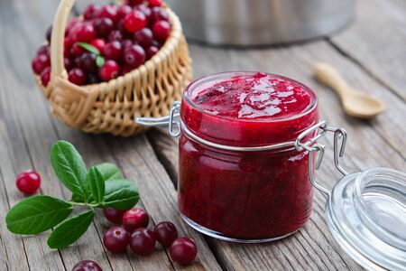 Jar of crushed cranberries for sauce or jam and basket of bog berriesの写真素材