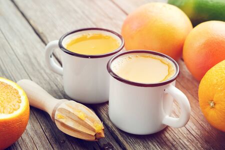 Two orange juice mugs, wooden juicer and citrus fruits.の写真素材