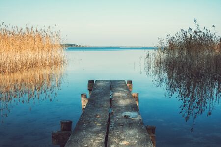 Wooden pier or footbridge on tranquil blue lake.の写真素材