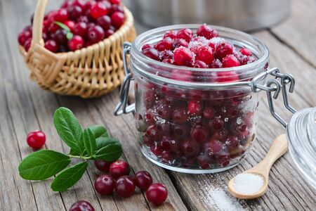 Jar of ripe cranberries with sugar, basket of bog berries and saucepanの写真素材