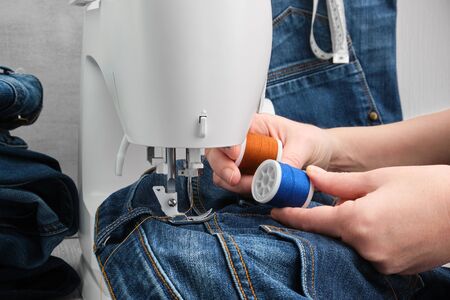 Sewing denim jeans on sewing machine in tailor workshop.の写真素材