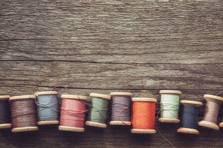 Row of vintage wooden spools of multicolored threads on wooden board.の写真素材