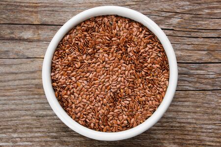 Bowl of whole flax seeds. Mortar of linseeds on wooden table, top view.の写真素材
