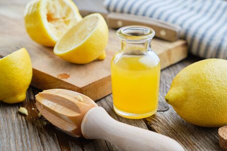 Lemon juice or oil bottle, wooden juicer and lemon citrus fruits.の写真素材